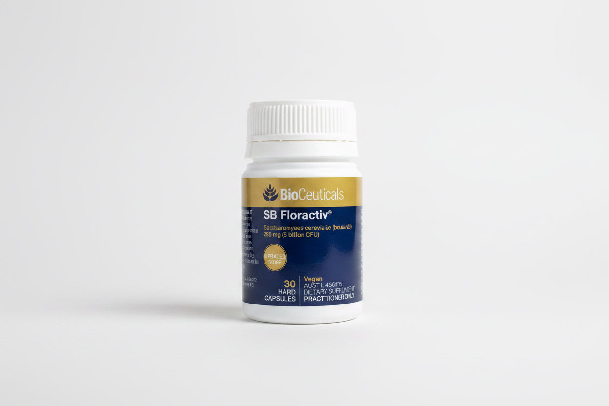 A white plastic bottle of BioCeuticals SB Floractiv dietary supplement capsules, featuring a gold and navy blue label, resting on a wooden surface.