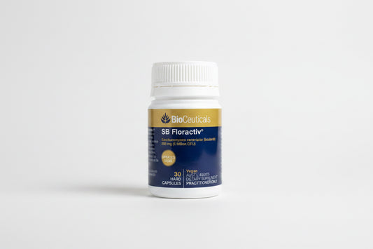 A white plastic bottle of BioCeuticals SB Floractiv dietary supplement capsules, featuring a gold and navy blue label, resting on a wooden surface.